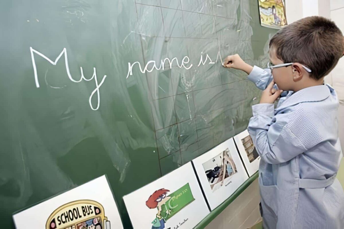 Niño escribe inglés en la pizarra del colegio