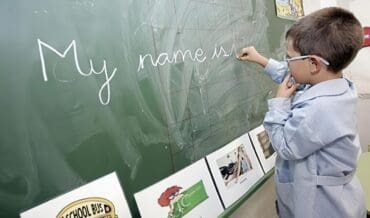 Niño escribe inglés en la pizarra del colegio